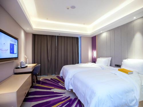 a hotel room with two beds and a flat screen tv at Lavande Hotel Chongqing West Station Baguo Cheng in Chongqing