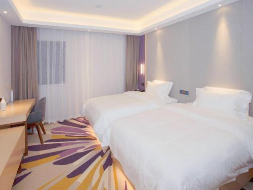 a hotel room with two beds and a desk at Lavande Hotels·Nanjing South of Olympic Stadium Daishan New Town in Nanjing