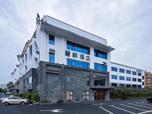 a white building with blue windows and a parking lot at Lavande Hotel National Sun Yat-sen University, Zhuhai in Zhuhai