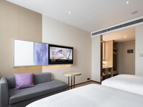 a bedroom with a bed and a couch and a tv at Lavande Hotel National Sun Yat-sen University, Zhuhai in Zhuhai