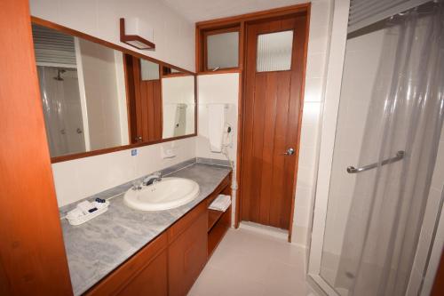 a bathroom with a sink and a mirror and a shower at D'Acosta Hotel Sochagota in Paipa