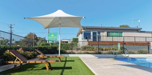 eine Terrasse mit zwei Bänken und einem Sonnenschirm neben einem Pool in der Unterkunft Crestview Tourist Park in Queanbeyan