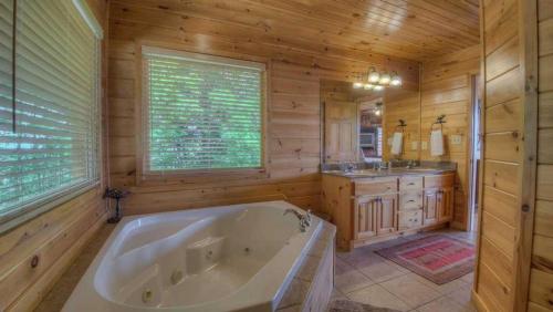ein großes Bad mit einer Badewanne und einem Waschbecken in einem Blockhaus in der Unterkunft High Five Lodge in Mineral Bluff