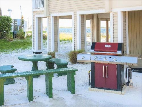 a picnic table and a grill next to a table and bench at GetAways at Soundside Holiday Beach Resort in Pensacola Beach