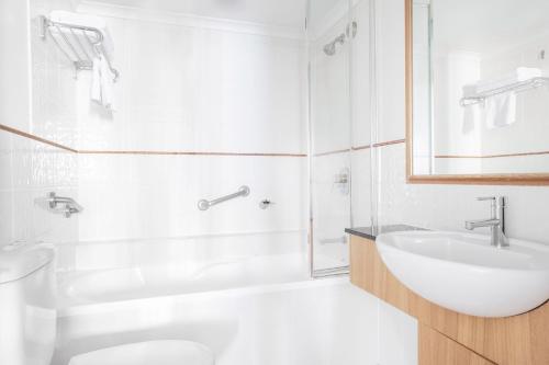 a white bathroom with a sink and a toilet at Mantra on Queen in Brisbane