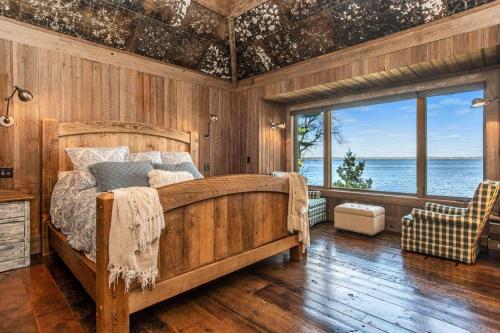 a bedroom with a bed and a view of the water at Gull Lakes Finest! Reclaimed Charm and Luxury in Lake Shore