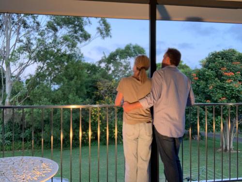 a man and a woman standing on a balcony looking out the window at Little Bank House in Mount Tamborine