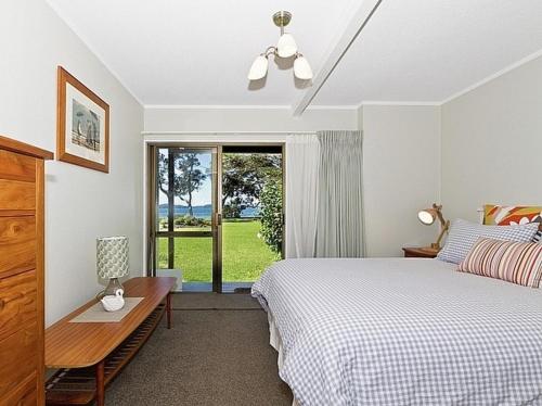 a bedroom with a bed and a table and a window at Beachside at Snells - Snells Beach Apartment in Snells Beach