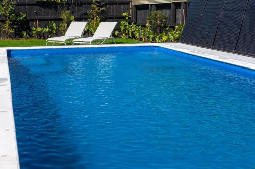 a blue swimming pool with two chairs next to it at Parkside Boutique Lodge in Rotorua
