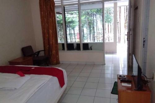 um quarto com uma cama e uma grande janela em RedDoorz near Lokawisata Baturaden 2 em Tenjo
