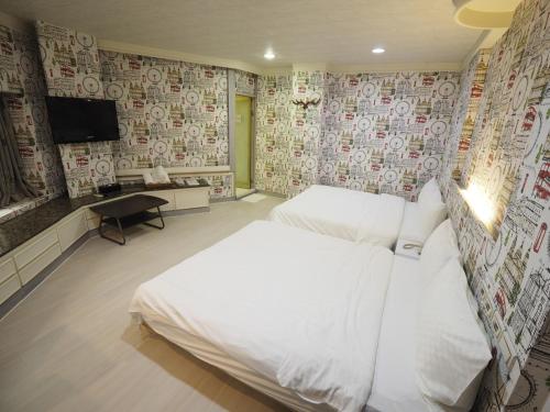 a bedroom with two beds and a flat screen tv at 合悅都會商旅 Heyue HOTEL in Hsinchu City