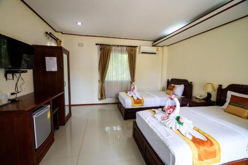 um quarto de hotel com duas camas e uma televisão em วันสุขรีสอร์ทสุโขทัย em Ban Khlong Takhian