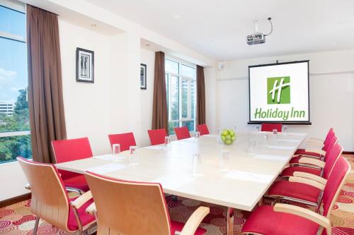 a conference room with a large white table and red chairs at Holiday Inn Dar Es Salaam by IHG in Dar es Salaam