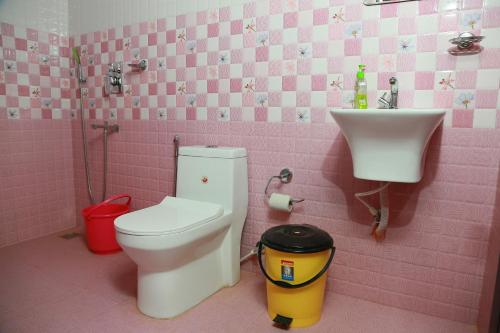 een roze badkamer met een toilet en een wastafel bij Marari Baiju's Homestay in Mararikulam