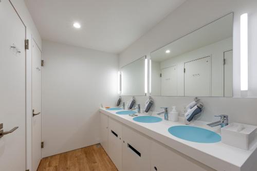 een badkamer met 3 wastafels en een grote spiegel bij plat hostel keikyu haneda home in Tokyo