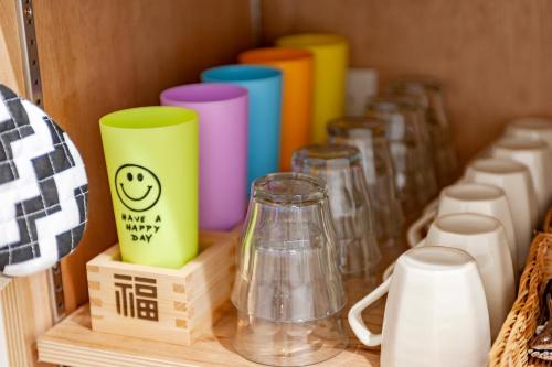 a group ofcolored cups sitting on a wooden shelf at plat hostel keikyu haneda home in Tokyo