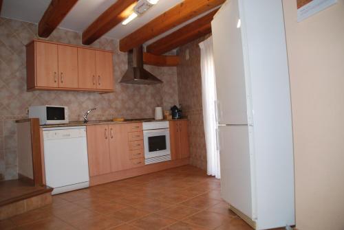 eine Küche mit einem weißen Kühlschrank und Holzschränken in der Unterkunft Casa La Catalina II in Beceite