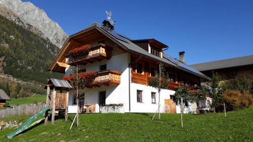 a house in the mountains with a slide in front of it at Unterreinischhof in Anterselva di Mezzo