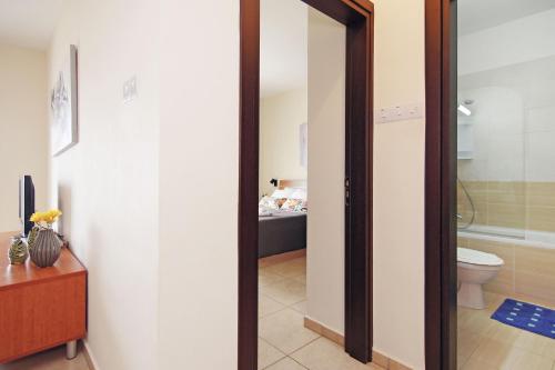 une salle de bains avec une porte s'ouvrant sur une salle de bains avec des toilettes. dans l'établissement Apartment Mariada, à Paralímni