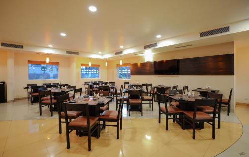 comedor con mesas y sillas y TV en Ginger Nashik, en Nashik