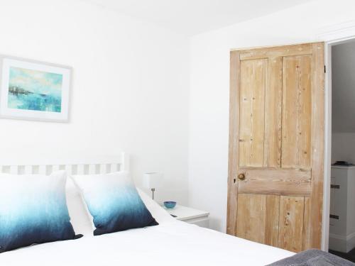 a bedroom with a white bed with a wooden door at The Eaves in Sandgate