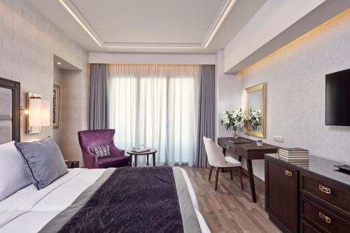 una camera d'albergo con letto, scrivania e TV di Electra Metropolis ad Atene