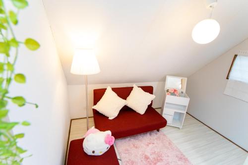 a small attic room with a red chair with pillows at Higashiomi Large House in Higashiomi