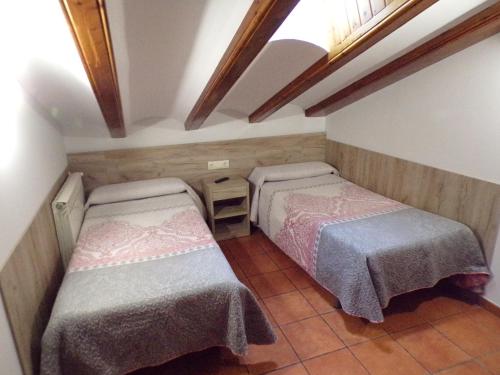 two beds in a small room with a window at Hostal Serruchi in Teruel