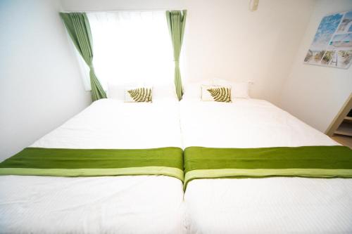 two beds in a room with a window at Higashiomi Large House in Higashiomi