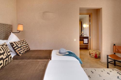 a bedroom with two beds with a hat on top at Oasis lodges in Marrakech