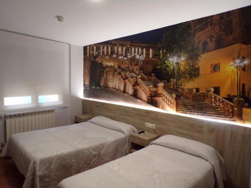 テルエルにあるHostal Serruchiの壁に絵画が飾られた部屋のベッド2台