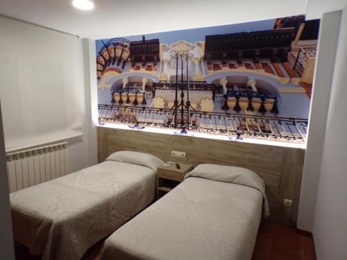 a room with two beds in a room with a building at Hostal Serruchi in Teruel