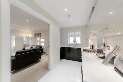 a large kitchen and living room with a black couch at Roomspace Serviced Apartments - Kinnaird Court in Esher