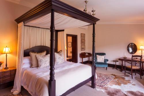 1 dormitorio con cama con dosel y mesa en Lalibela Game Reserve - Mills Manor, en Paterson