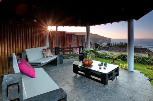 a patio with a bench and a table with a view of the ocean at Retiro do Tico in Porto Formoso
