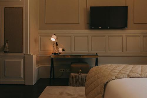 a bedroom with a bed and a desk with a television on the wall at Torel 1884 Suites & Apartments in Porto