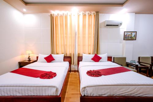 two beds in a hotel room with red pillows at Hoang Duc Hotel in Chau Doc