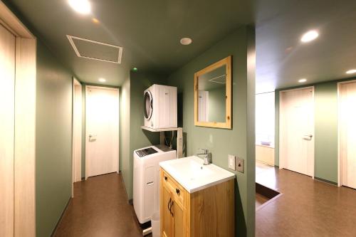 eine grüne Küche mit einer Spüle und einer Mikrowelle in der Unterkunft Guesthouse & Lounge FARO in Iwaki