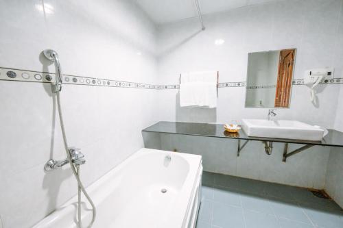 a white bathroom with a tub and a sink at Hoang Duc Hotel in Chau Doc