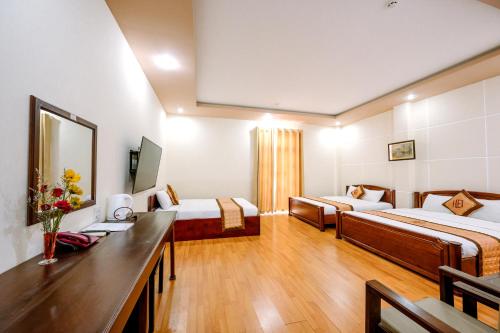 a hotel room with two beds and a desk at Hoang Duc Hotel in Chau Doc
