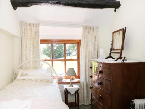 a bedroom with a bed and a dresser and a window at Undercragg in Seathwaite