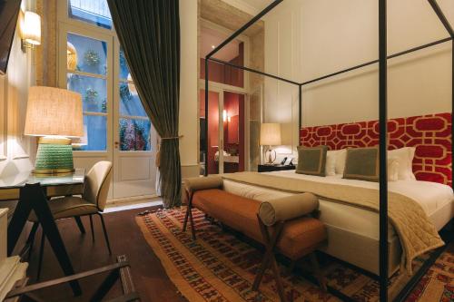 a hotel room with a bed and a desk and a window at Torel 1884 Suites & Apartments in Porto