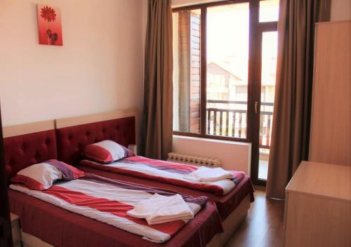 two beds in a room with a large window at PM Services Semiramida Apartments in Borovets