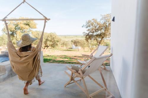 a woman sitting in a hammock next to a chair at Montimerso Skyscape Countryhouse in Monsaraz