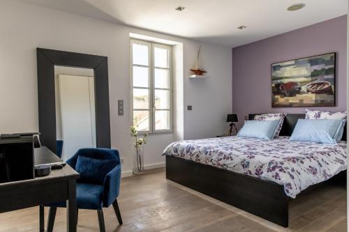 ein Schlafzimmer mit einem Bett und einem blauen Stuhl in der Unterkunft LA BASTIDE DE FANGOUSE in Entrecasteaux