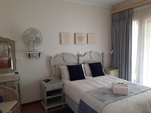 a bedroom with a large white bed with blue pillows at Sandstone Chameleon Guest House in Fouriesburg