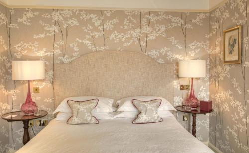 a bedroom with a white bed with two tables at Gravetye Manor in East Grinstead