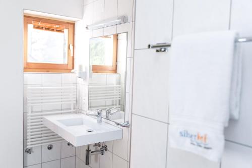 a white bathroom with a sink and a mirror at Silserhof - ankommen, auftanken, aufatmen in Sils Maria