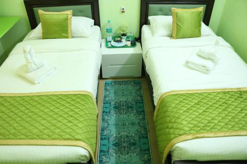 two beds sitting next to each other in a room at Hotel NKC Airport in Chennai