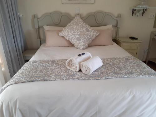 a bed with two towels and pillows on it at Sandstone Chameleon Guest House in Fouriesburg